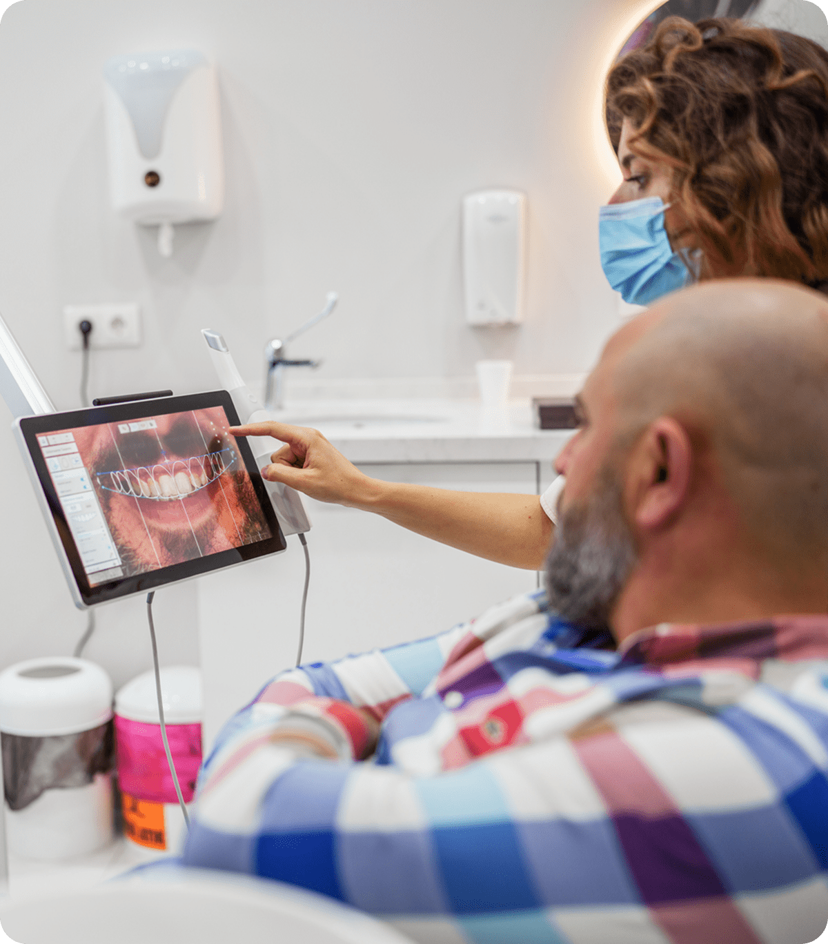 Dentist showing dental X-ray on tablet.